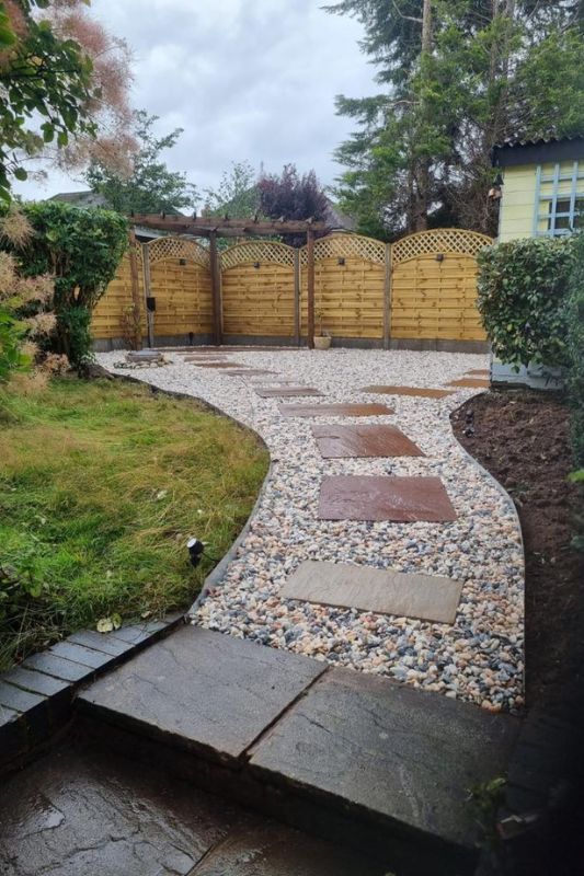 Landscaping works completed in Solihull. Natural stone pavers laid as a pathway with decorative gravel and EverEdge flexible metal garden edging on upper level of garden transformation works.