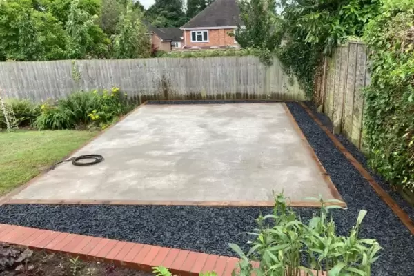 Concrete pad base installed for garden office studio space with decorative borders in residential garden.