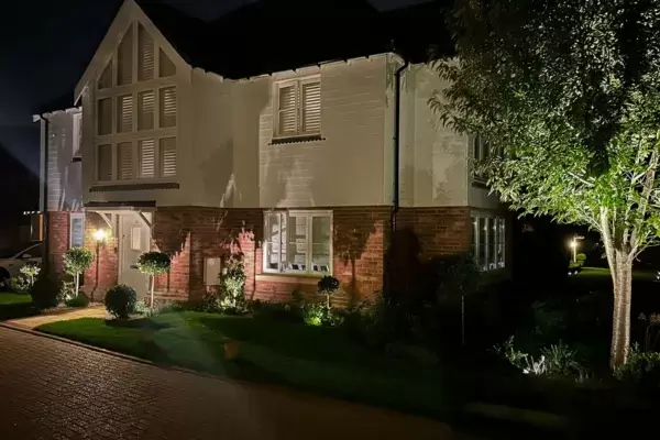 Contemporary home front exterior illuminated by low voltage outdoor lighting installed in borders around front of house.