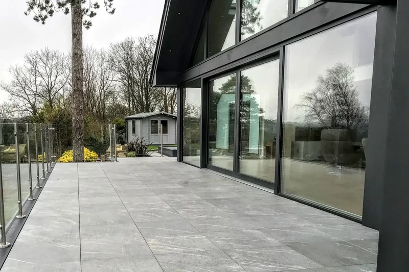 Large detached contemporary extension with raised deck terrace, outdoor porcelain tiles and balustrade installed using the iGarden light steel subframe foundation system.