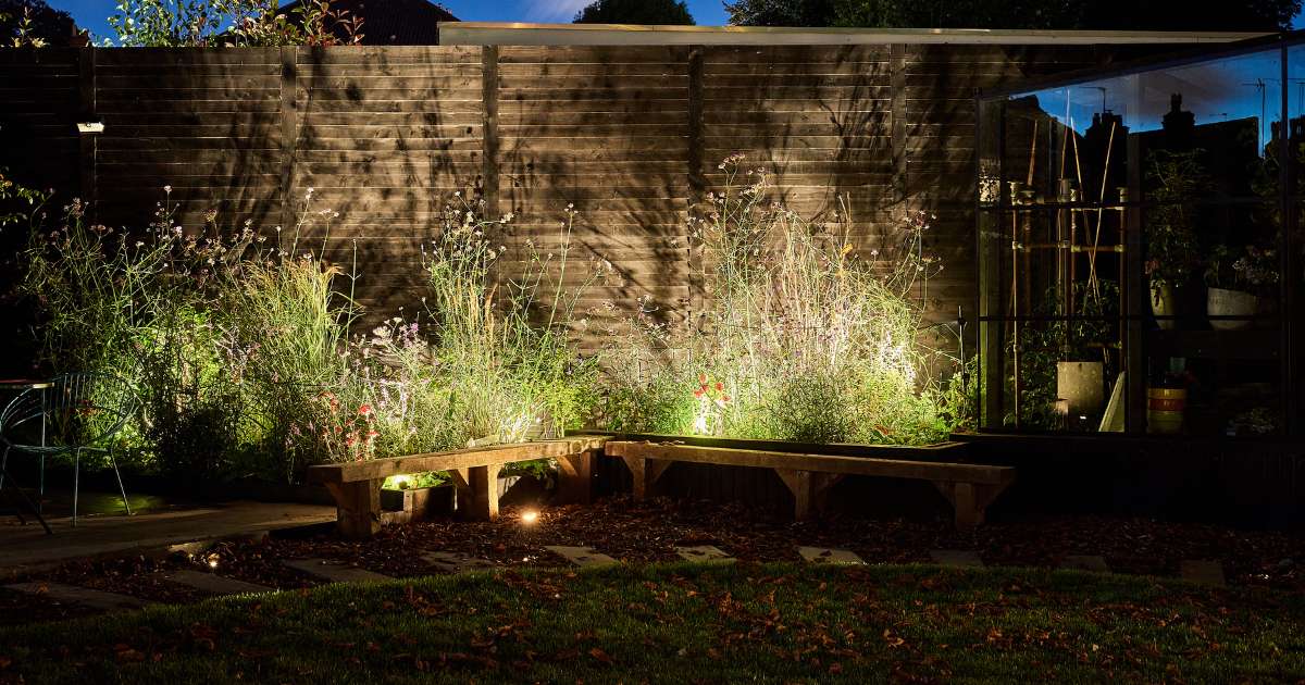 12v outdoor garden lighting installation completed in Harborne Birmingham. Low voltage outdoor spotlights illuminating variety of plants in planting beds along curved garden path - Oakland Group, Outdoor Garden Lighting Design and Installation Services.
