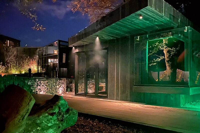 Patio decking outdoor space, garden studio, gabion walls with atmospheric lighting at night.