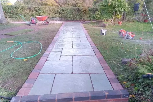Garden pathway build with natural stone paving and block edge in rear landscape.