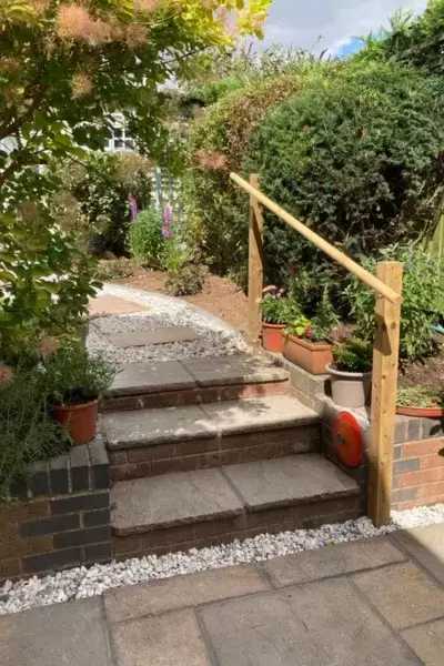 Refurbished patio and steps with timber handrail leading up to renovated garden upper level.