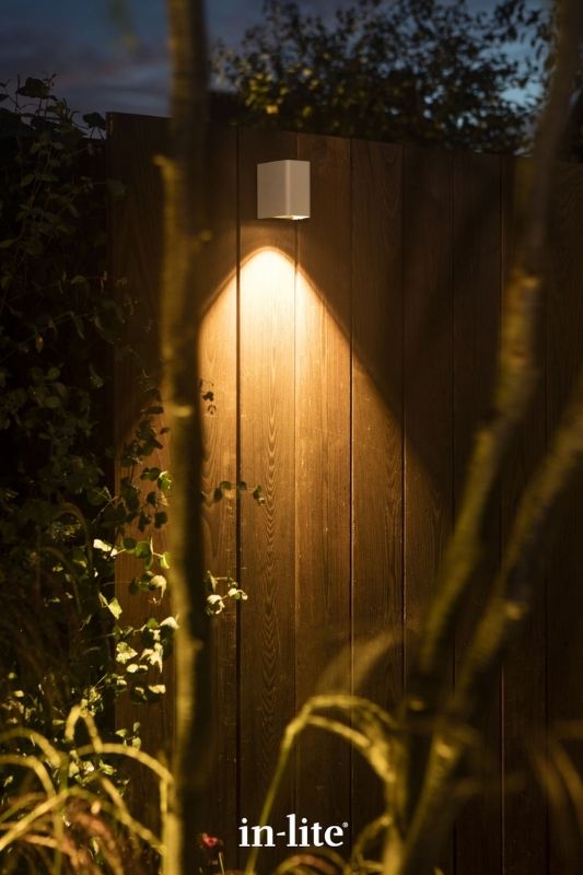 in-lite ACE DOWN WHITE 12v outdoor wall lights, installed along fence panelling, illuminating downwards with a targeted beam light to the ground. Low voltage outdoor garden lights, atmospheric lighting for ambiance.