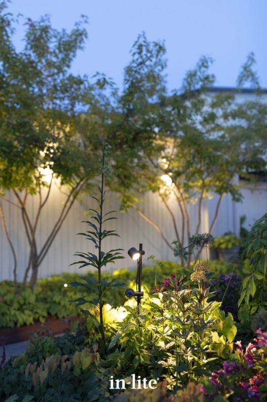 in-lite MINI SCOPE DUO 12v outdoor spotlights, mounted on a separable stand and ground stake, illuminating plants with soft warm white lighting in different angles and directions. Low voltage outdoor garden lights, atmospheric lighting for ambiance.