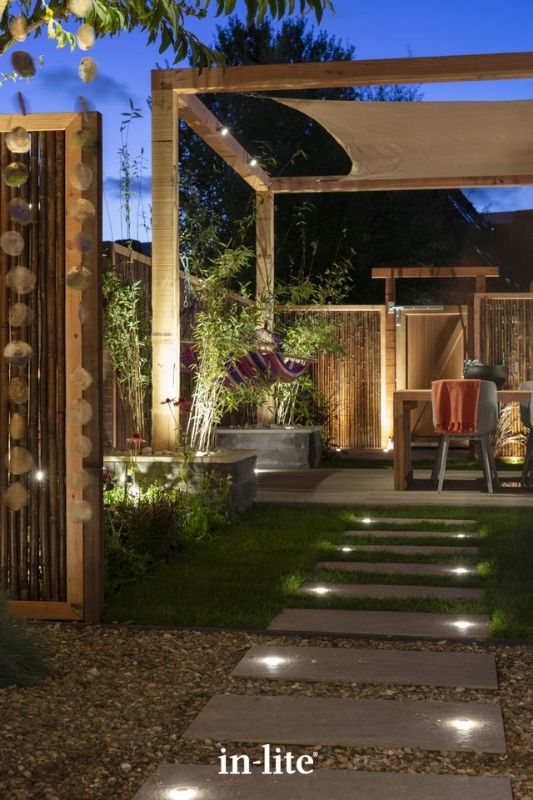 in-lite PUCK 22 12v outdoor recessed lights providing indicative lighting installed in pavers along garden path leading to a pergola and an outdoor living space. Low voltage outdoor garden lights, atmospheric lighting for ambiance.