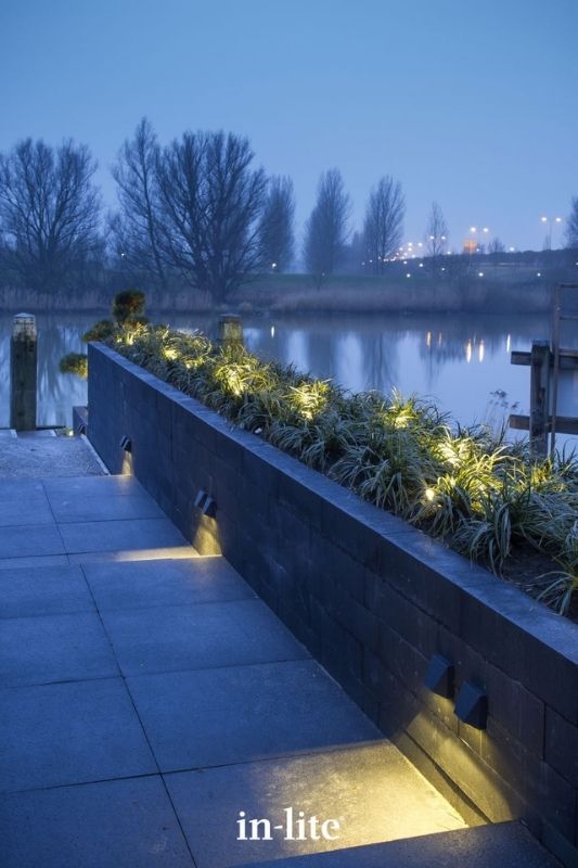 in-lite WEDGE DARK 12v outdoor wall lights installed on wall suraface, illuminating along paved step levels with a targeted warm white beam of downwards light. Low voltage outdoor garden lights, atmospheric lighting for ambiance.