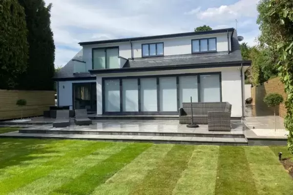 Contemporary home extension and raised patio terraces with outdoor porcelain, new lawn, lighting and slatted fencing installed.