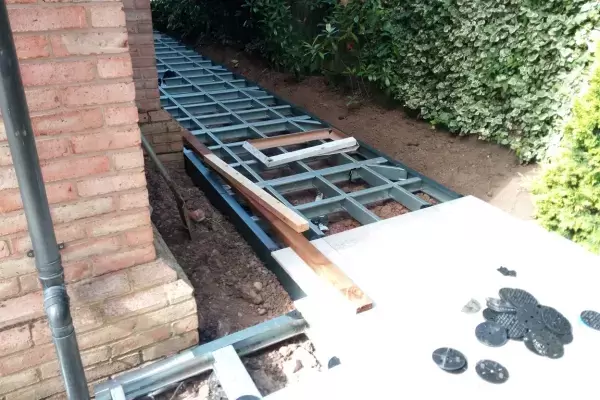 Porcelain patio sub frame system installed over existing ground around side access of property.