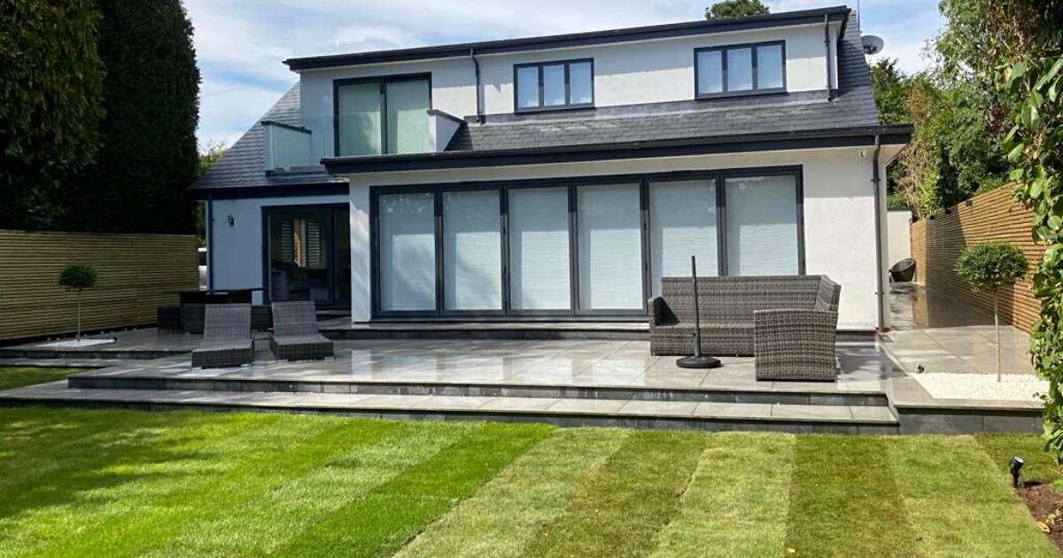 Professional landscaping works completed to design contemporary porcelain wraparound patio, pathway and slatted fencing with low voltage outdoor wall lights installed - Oakland Group, Landscaping Services.