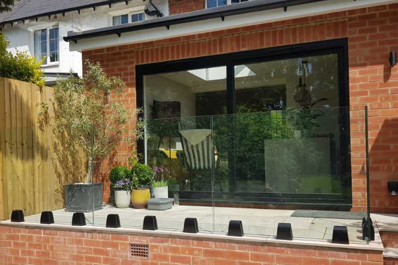 Landscaping works in Knowle, Solihull. Glass balustrade installation works completed. Frameless glass balustrade system with toughened laminate glass panels and adjustable glass clamps installed and aligned onto raised patio for safety and aesthetics.