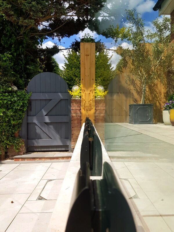 Landscaping works completed in Knowle Solihull. Glass balustrade system installed on natural stone raised patio.