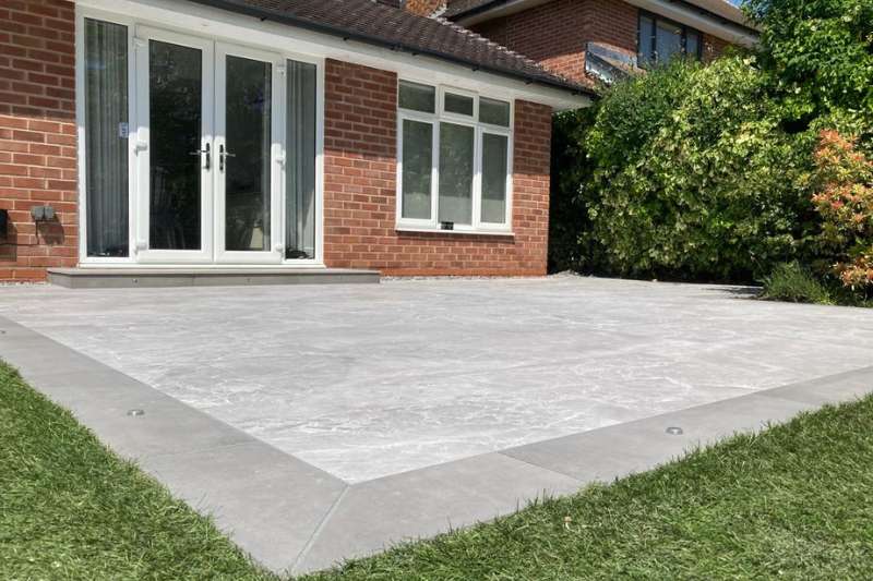 Landscaping works in Dorridge, Solihull. New porcelain patio build completed with low voltage outdoor lighting installed. Prima porcelain outdoor tiles. Main patio consists of 2cm Marble Light Grey 60 x 90cm. Patio border consists of 2cm Cemento Grey 45x90cm. in-lite HYVE 22 RVS 12v outdoor decking lights recessed in step risers. in-lite PUCK 22 12v outdoor decking lights recessed in paving border around main patio.