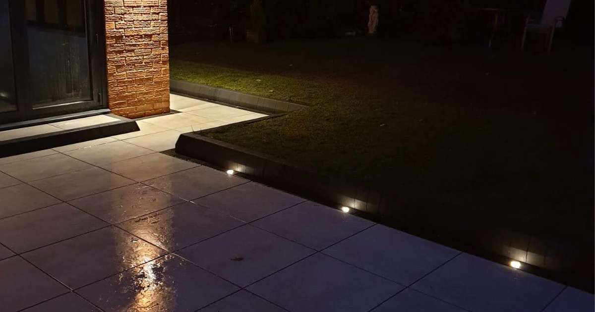 Professional landscaping works completed contemporary porcelain patio with block edge and low voltage outdoor lighting softly illuminating along the patio border - Oakland Group, Landscaping Services.