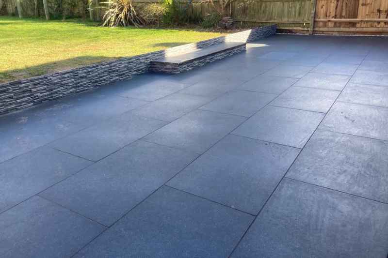 Patio landscaping works in Solihull. Patio build complete with new paving and stone cladded wall and step.