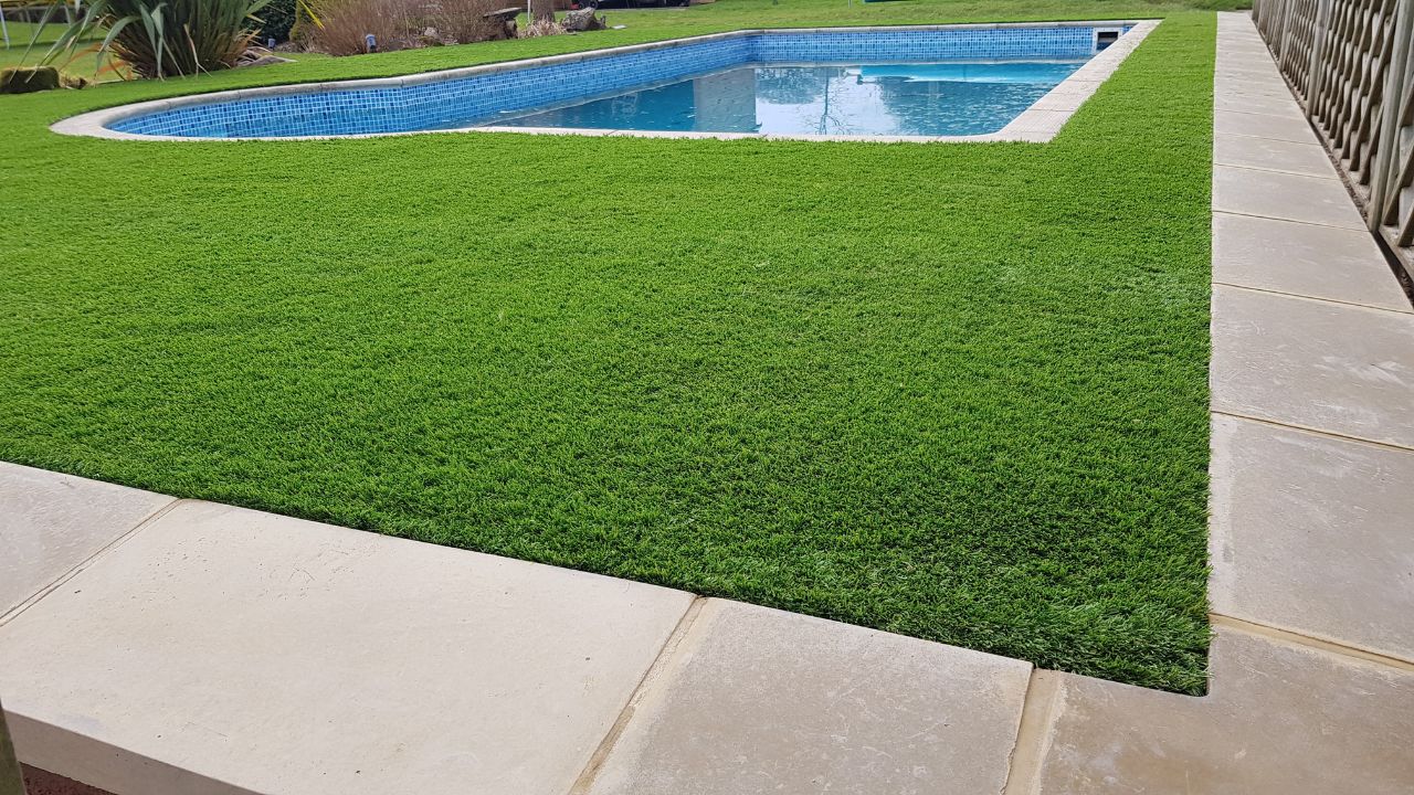 Landscaping works completed in Rowington Warwick. Artificial grass and large coping stones installed around swimming pool in private garden residence.