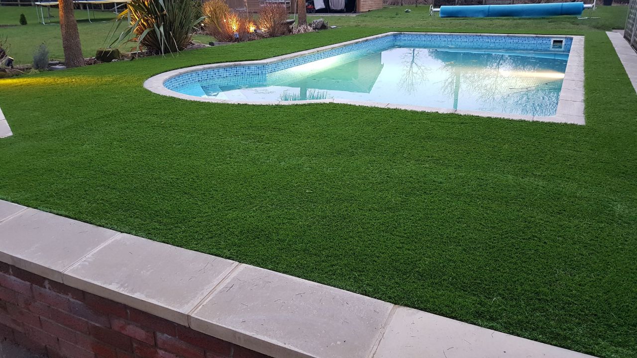 Landscaping works completed in Rowington Warwick. Artificial grass and large coping stones installed around swimming pool in private garden residence.