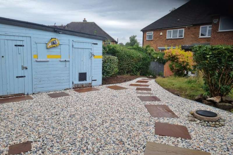Landscaping works completed in Solihull. Natural stone pathway with decorative gravel, stone water feature, and EverEdge flexible metal garden edging on upper level of garden transformation works.