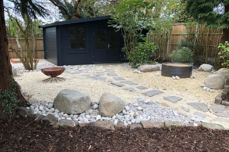 Landscaping works completed in Solihull. New gravel feature area with 'Cracked River bed' footpath leading to contemporary outbuilding gym. New Gravel Feature Area with 'Cracked River bed' footpath. Scottish Beach Cobbles and Scottish Boulders. Large Corten steel fire bowl in situ.