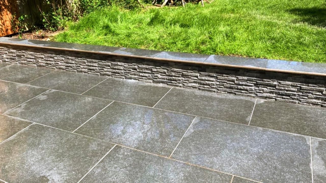 Landscaping works completed in Solihull. Stone patio, step and retaining wall built with stone cladding and coping stone surface finish.