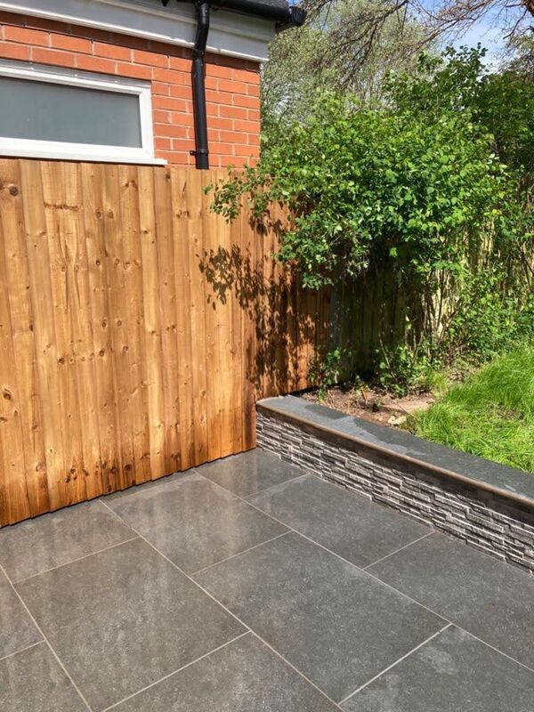 Landscaping works completed in Solihull. Stone patio, step and retaining wall built with stone cladding and coping stone surface finish.