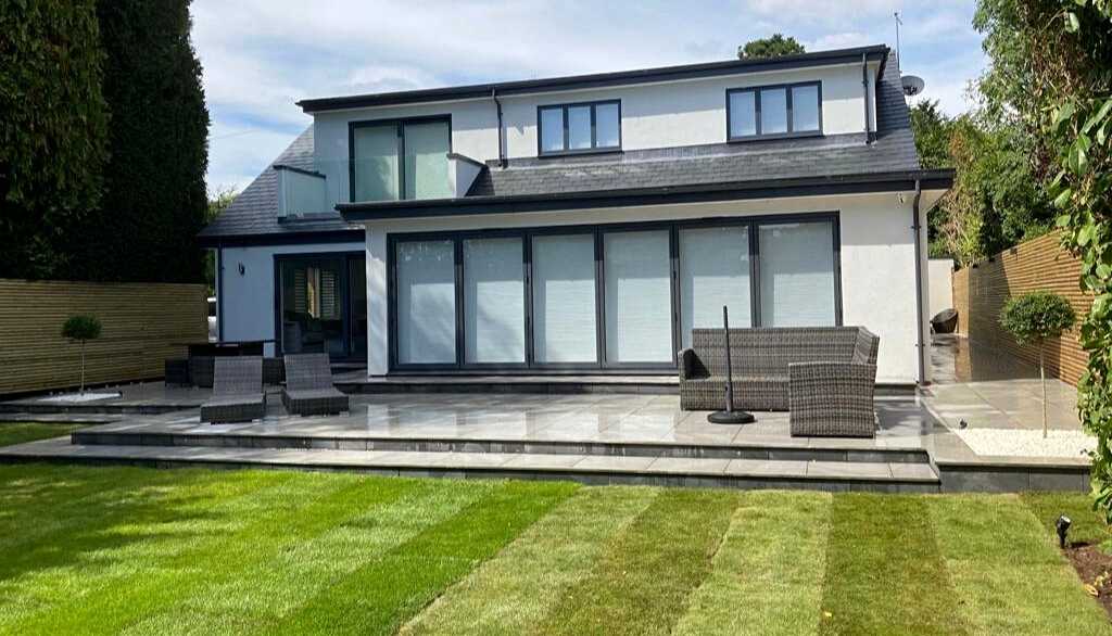 Contemporary new build home extension with porcelain patio terraces and low voltage lighting for luxury garden outdoor living space in Dorridge, Solihull - Oakland Group.