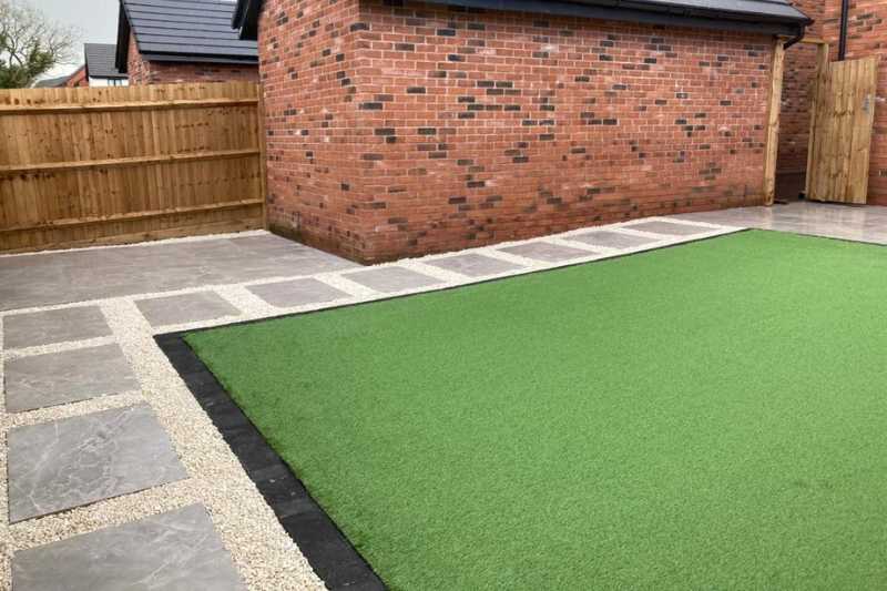 New build garden landscaping works, porcelain patio and pathways with block edge and decorative gravel surrounding artificial lawn in the new build garden. Bloor Homes at Blythe Valley, Solihull - Oakland Group.
