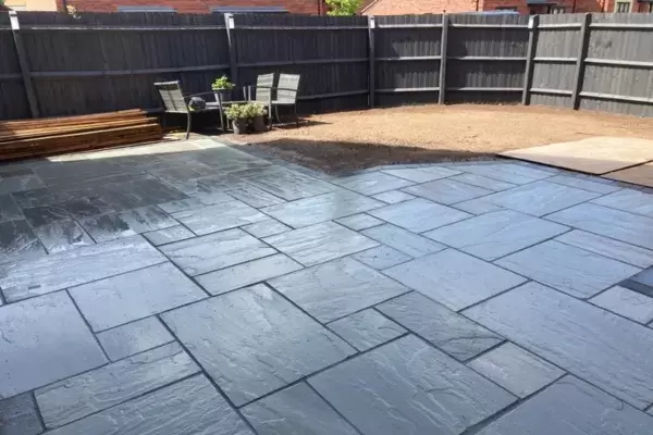 New patio laid with Kandla grey sandstone paving slabs and block edge border.
