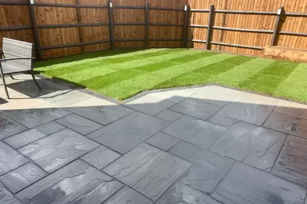 New patio built of Kandla Grey natural stone paving slabs with lawn turf and fencing installed in new rear garden.