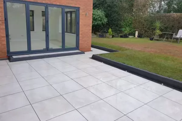 Porcelain patio, step and pathway with block edge installed around in rear garden around a new home extension.