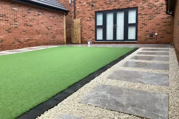 Porcelain patio and porcelain paving slabs creating a steping stone path along artificial grass area with block edge in low maintenance garden.