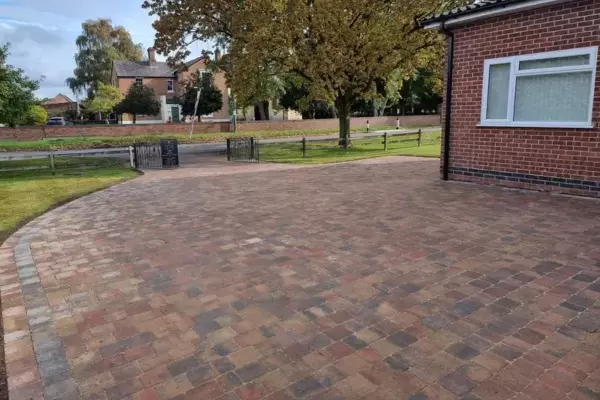 Block paved driveway with Tobermore tumbled paving installed around front of property landscape.